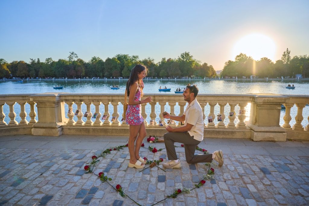 Pareja junto al lago del Parque del Retiro con el atardecer reflejado en el agua durante una pedida de mano en Madrid